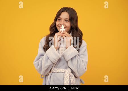 Fille tenir médicament spray nasal de nez courant, pandémie de virus. Jeune fille malade avec vaporisateur nasal sur fond jaune. Banque D'Images