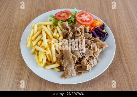 Kebab sur une assiette de salade de pommes de terre frites et de légumes. Banque D'Images