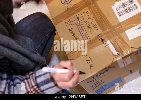 Hambourg, Allemagne. 07th févr. 2023. Une femme étiquette une boîte en carton dans le cadre d'une campagne de collecte de fonds privée dans un bar fermé à Hambourg-Altona. Suite au grave tremblement de terre dans la zone frontalière turco-syrienne, des expéditions d'aide contenant des articles tels que des vêtements, des couvertures, des produits pour bébés et des articles d'hygiène sont collectées et envoyées en Turquie. Crédit : Bodo Marks/Bodo Marks/dpa/Alay Live News Banque D'Images