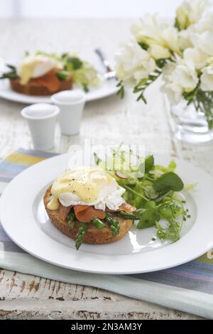 Asperges et œufs de saumon fumé benedict avec feuilles vertes sur une assiette blanche Banque D'Images