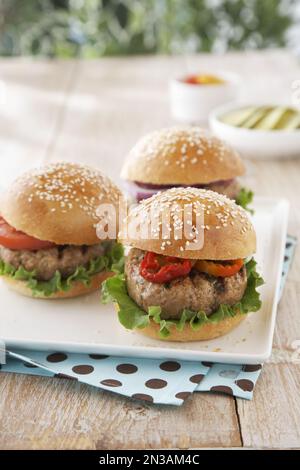 Hamburgers de bœuf grillés avec garnitures sur table en bois Banque D'Images