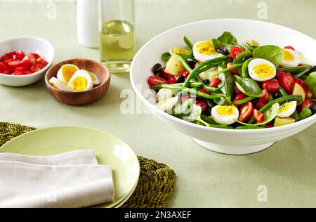 Salade niçoise aux œufs, haricots verts, tomates et olives sur une nappe en lin vert Banque D'Images