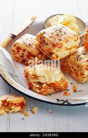 Biscuits au bacon et au fromage avec du beurre sur une assiette blanche rustique Banque D'Images