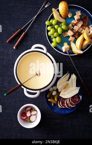 Fondue au fromage avec légumes et fruits pour un trempage sur fond bleu foncé Banque D'Images