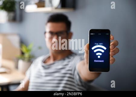 Homme se connectant au Wi-Fi à l'aide d'un téléphone mobile à l'intérieur, concentrez-vous sur l'appareil Banque D'Images