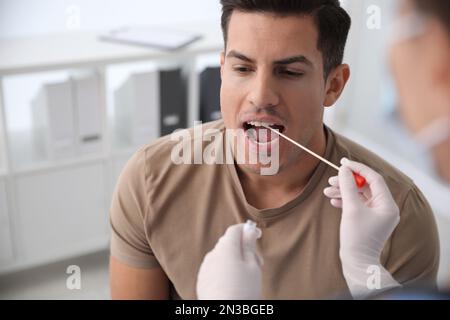 Médecin prenant l'échantillon pour le test d'ADN de l'homme en clinique Banque D'Images