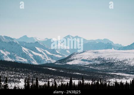 Les montagnes enneigées près des glaciers Nelchina et Tazlina s'élèvent au-dessus des forêts d'épinettes noires et de la Glenn Highway, près d'Eureka et de Sheep Moun... Banque D'Images