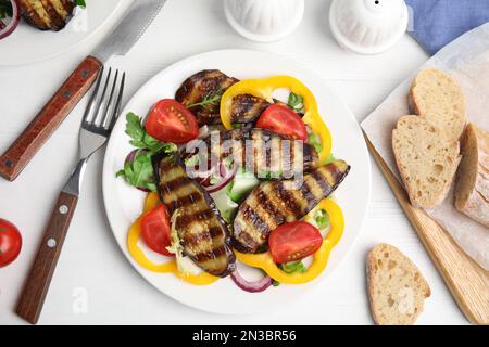 Salade délicieuse aux aubergines rôties, servie sur une table en bois blanc, sur une table plate Banque D'Images