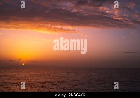 Paysage incroyable d'un magnifique coucher de soleil sur la mer. Lumière orange douce dans le ciel du soir. Belle plage paisible. Nature du Liban. Banque D'Images