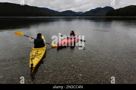 Père et fille font du kayak sur l'eau plate près de l'île Moser qui sépare les bras Nord et Sud Hoonah Sound sur l'île Chichagof à Tongass Nationa... Banque D'Images