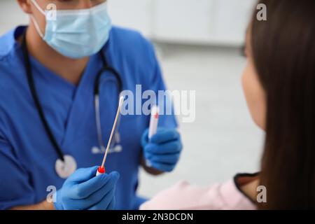 Médecin prenant l'échantillon pour le test d'ADN de la femme en clinique Banque D'Images