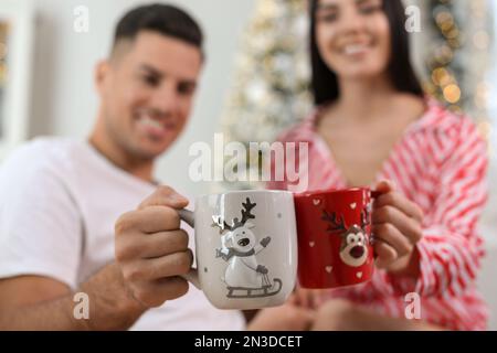 Couple de brunissage avec des tasses à la maison, concentrez-vous sur les mains. Fête de Noël Banque D'Images