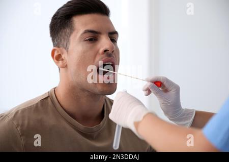 Médecin prenant l'échantillon pour le test d'ADN de l'homme en clinique Banque D'Images