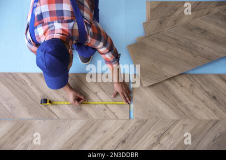 Travailleur installant un plancher en bois laminé à l'intérieur, au-dessus de la vue Banque D'Images