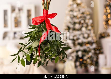 Bouquet de GUI avec noeud rouge suspendu dans la chambre décorée pour Noël Banque D'Images