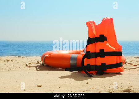 Gilet de sauvetage orange et bouée sur une plage de sable près de la mer. Équipement de secours Banque D'Images