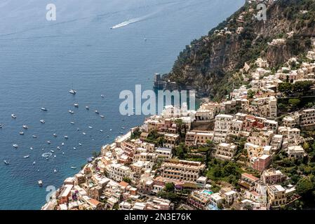 Vue aérienne des bâtiments en pierre et des terrasses sur la falaise dans la ville de Positano avec des bateaux amarrés le long de la côte amalfitaine Banque D'Images