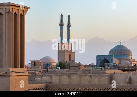 Vue d'ensemble de la mosquée Jamesh de Yazd au coucher du soleil avec la silhouette douce de la montagne Zagros au loin ; ville de Yazd, province de Yazd, Iran Banque D'Images