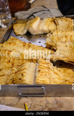 Cabillaud salé bacalhau grillé sur bois de chauffage en bois d'olive dans le petit restaurant du village au Portugal, prêt à manger Banque D'Images