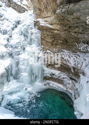 Beauté d'hiver dans Johnston Canyon, formations de glace le long d'un mur de roche et d'une piscine turquoise au-dessous des chutes inférieures gelées; Alberta, Canada Banque D'Images