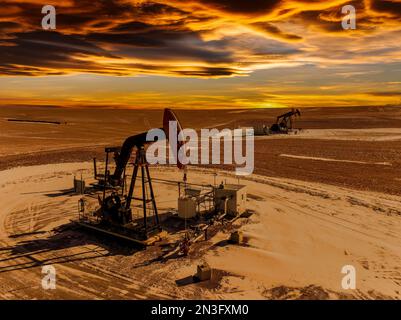 Vue aérienne de deux citrouilles dans un champ enneigé avec un ciel couvert de nuages colorés au coucher du soleil, à l'ouest d'Airdrie; Alberta, Canada Banque D'Images