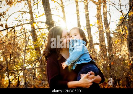 Portrait d'une mère et de sa petite fille avec le syndrome de Down passant du temps de qualité à l'extérieur pendant une sortie familiale dans un parc de la ville en automne Banque D'Images