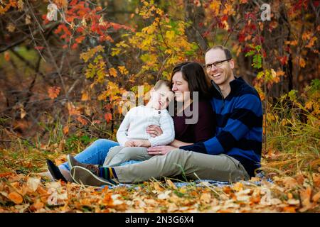 Une mère et un père passent un peu de temps de qualtiy avec leur fils lors d'une sortie en famille dans un parc de la ville pendant la saison d'automne Banque D'Images