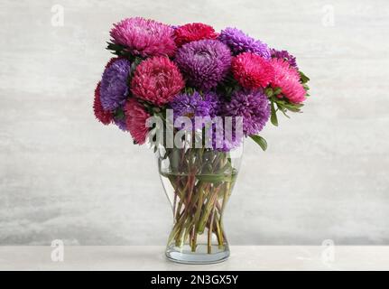 Beaux dessous-de-verre dans un vase sur une table sur fond blanc. Fleurs d'automne Banque D'Images