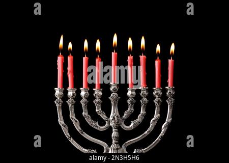 Menorah argentée avec bougies allumées sur fond noir. Célébration Hanukkah Banque D'Images