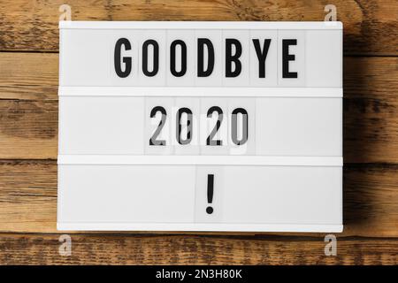 Visionneuse avec phrase Au revoir 2020 ! sur une table en bois, vue du dessus Banque D'Images