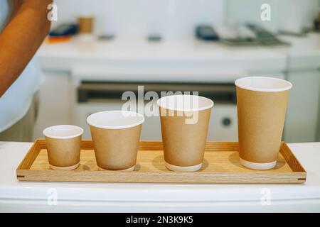 Solution de café écologique : quatre tailles de tasses à café jetables sur un plateau en bois Parfaits pour les plats à emporter, les tasses sont en carton et en mousse, s Banque D'Images