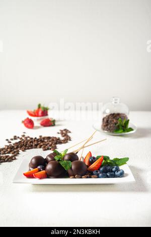 Fraises et bleuets trempés au chocolat sur une assiette blanche. Mise au point sélective. Banque D'Images