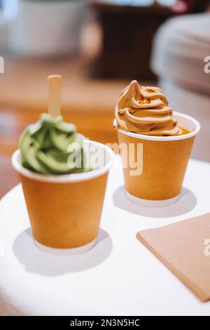 Une dose appétissante de deux boules de glace, avec une cuillère à saveur de matcha en flou de premier plan et focalisée une glace au chocolat Banque D'Images