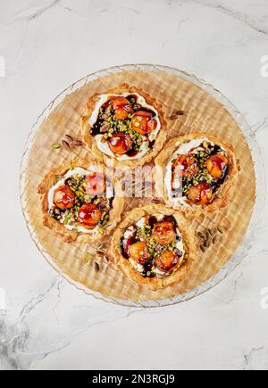 Tartelettes au melon, mascarpone et pistaches sur une plaque transparente Banque D'Images