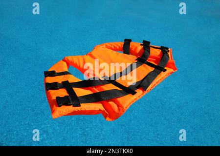 Gilet de sauvetage orange vif flottant dans la piscine Banque D'Images