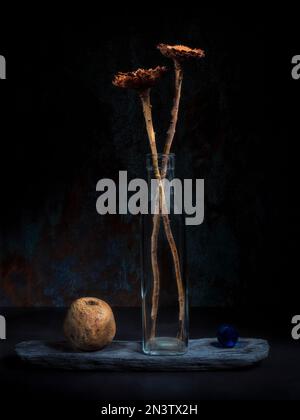 Encore la vie avec des fleurs séchées en bouteille de verre à côté de boule de verre et de boule de bois Banque D'Images