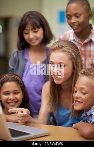 Montrer quelque chose à ses amis sur son pc pendant le cours sur l'ordinateur. Un groupe d'élèves travaillant sur un ordinateur portable en classe. Banque D'Images