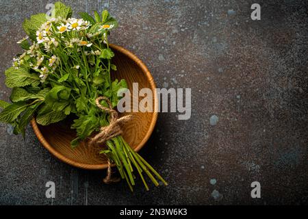 Bouquet de fleurs sauvages fraîches et herbes curatives dans un bol en bois rustique vue de dessus plat Lay sur fond de pierre pour la médecine alternative de fines herbes et Banque D'Images