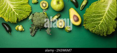 Mise en page créative concept alimentaire fait de fruits et légumes verts sur fond vert plat lay: Avocat, chou frisé, brocoli, choux de Bruxelles, kiwi Banque D'Images
