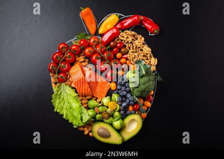 Une alimentation saine et une alimentation pour le système cardiaque et cardiovasculaire, une alimentation saine, des fruits et des légumes en forme de coeur réaliste sur le noir Banque D'Images