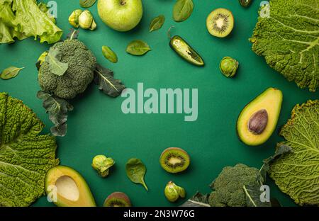 Mise en page créative concept alimentaire fait de fruits et légumes verts sur fond vert plat lay: Avocat, chou frisé, brocoli, choux de Bruxelles, kiwi Banque D'Images