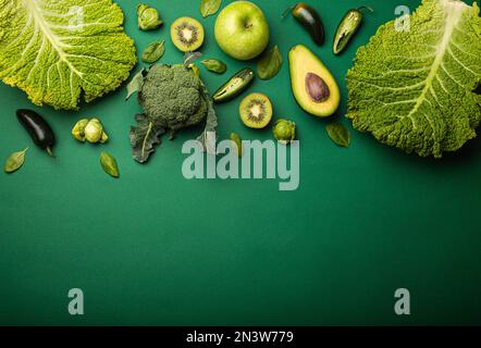 Mise en page créative concept alimentaire fait de fruits et légumes verts sur fond vert plat lay: Avocat, chou frisé, brocoli, choux de Bruxelles, kiwi Banque D'Images
