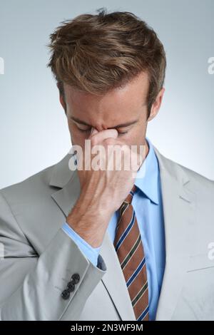 Quand les choses deviennent trop... un jeune homme d'affaires montrant des signes de stress au travail. Banque D'Images