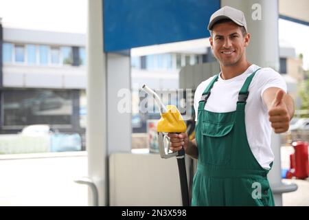 Employé avec buse de pompe à carburant à la station-service moderne Banque D'Images