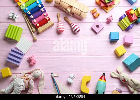 Cadre fait de différents jouets sur fond de bois rose, plat. Espace pour le texte Banque D'Images