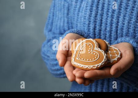 Femme avec de savoureux biscuits de pain d'épice en forme de coeur sur fond bleu, gros plan Banque D'Images