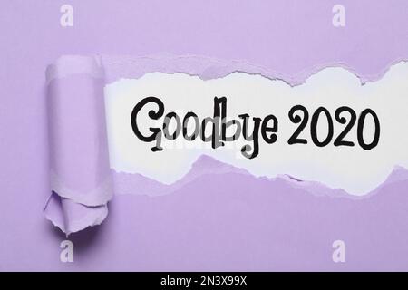 Texte Au revoir 2020 sur fond blanc, vue de dessus à travers le papier lilas déchiré Banque D'Images