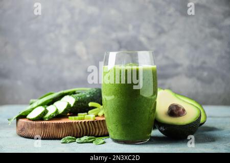 Délicieux jus de fruits verts et ingrédients frais sur une table en bois bleu clair sur fond gris Banque D'Images