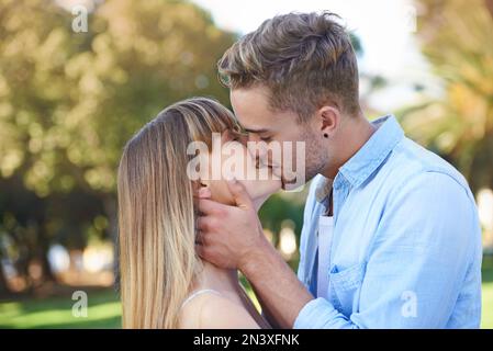 True aime le premier baiser. un jeune couple partage un moment d'appel d'offres dans le parc. Banque D'Images