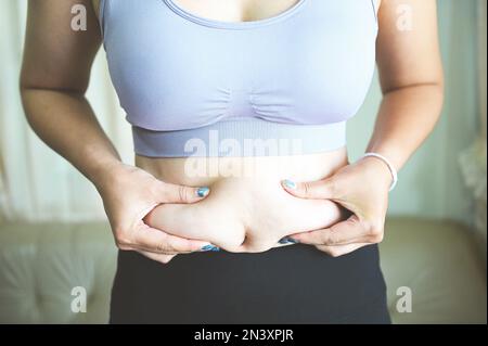 FAT femme mesure , graisse femme ventre gros chubby paunchy sport récréation santé perte de graisse du ventre concept, femme tenant le ventre excessif Banque D'Images